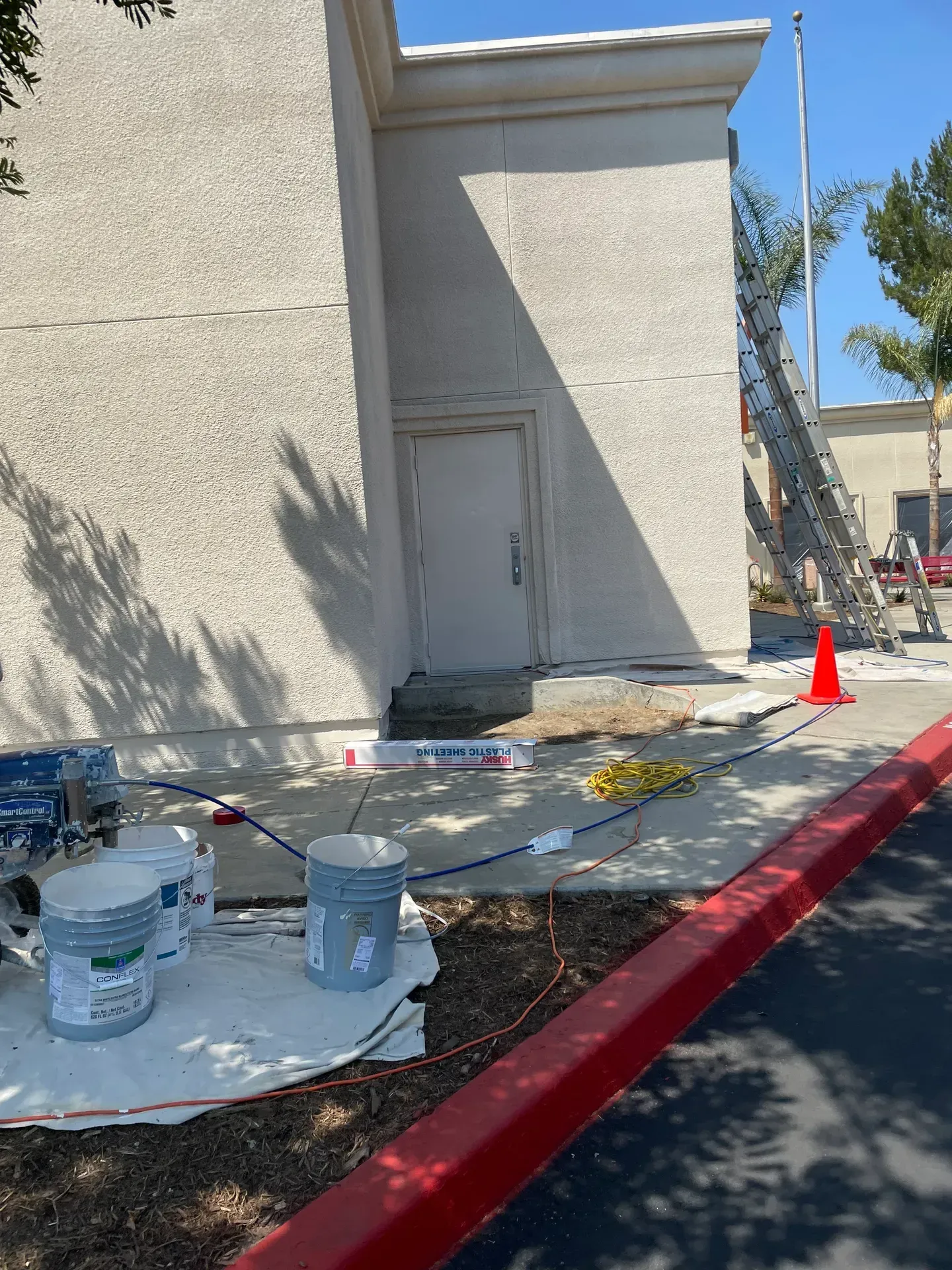 Buckets of paint are sitting on a table in front of a building being painted.