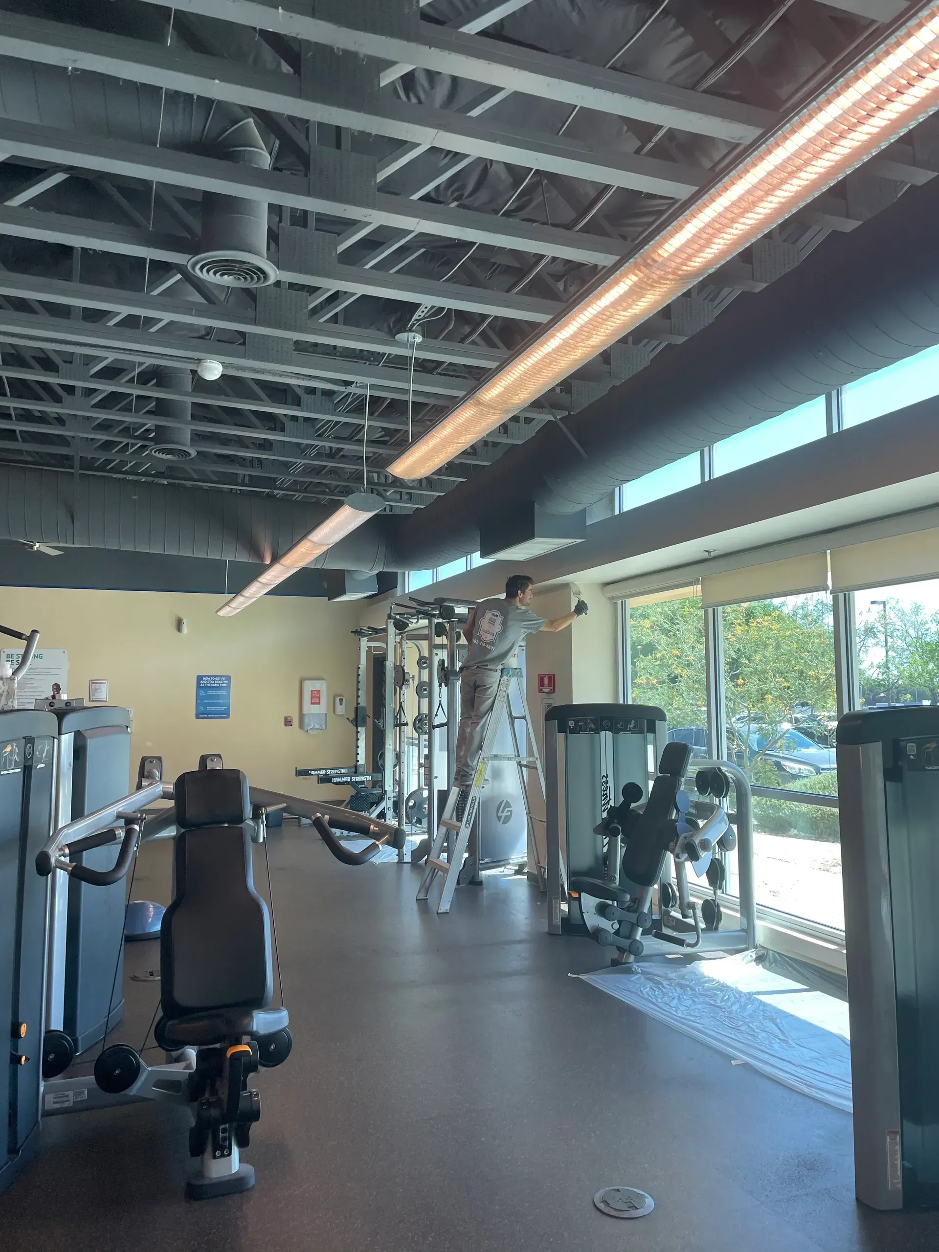 A gym with a lot of exercise equipment and a large window