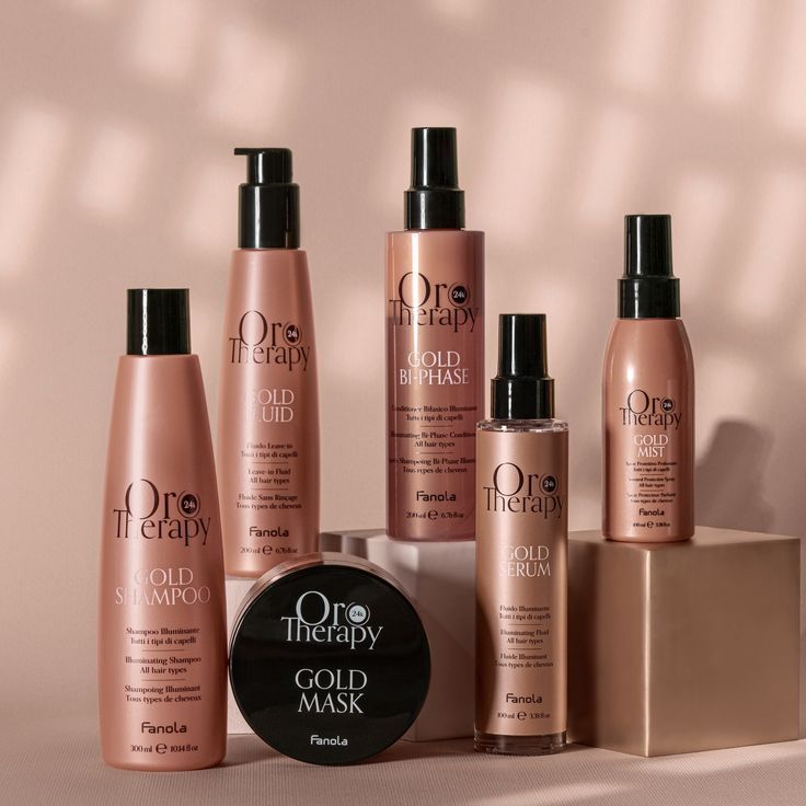 Een set haarproducten van Oro Therapy, gepresenteerd in een display. Inclusief flesjes en een potje in een goud- en roze kleurstelling.