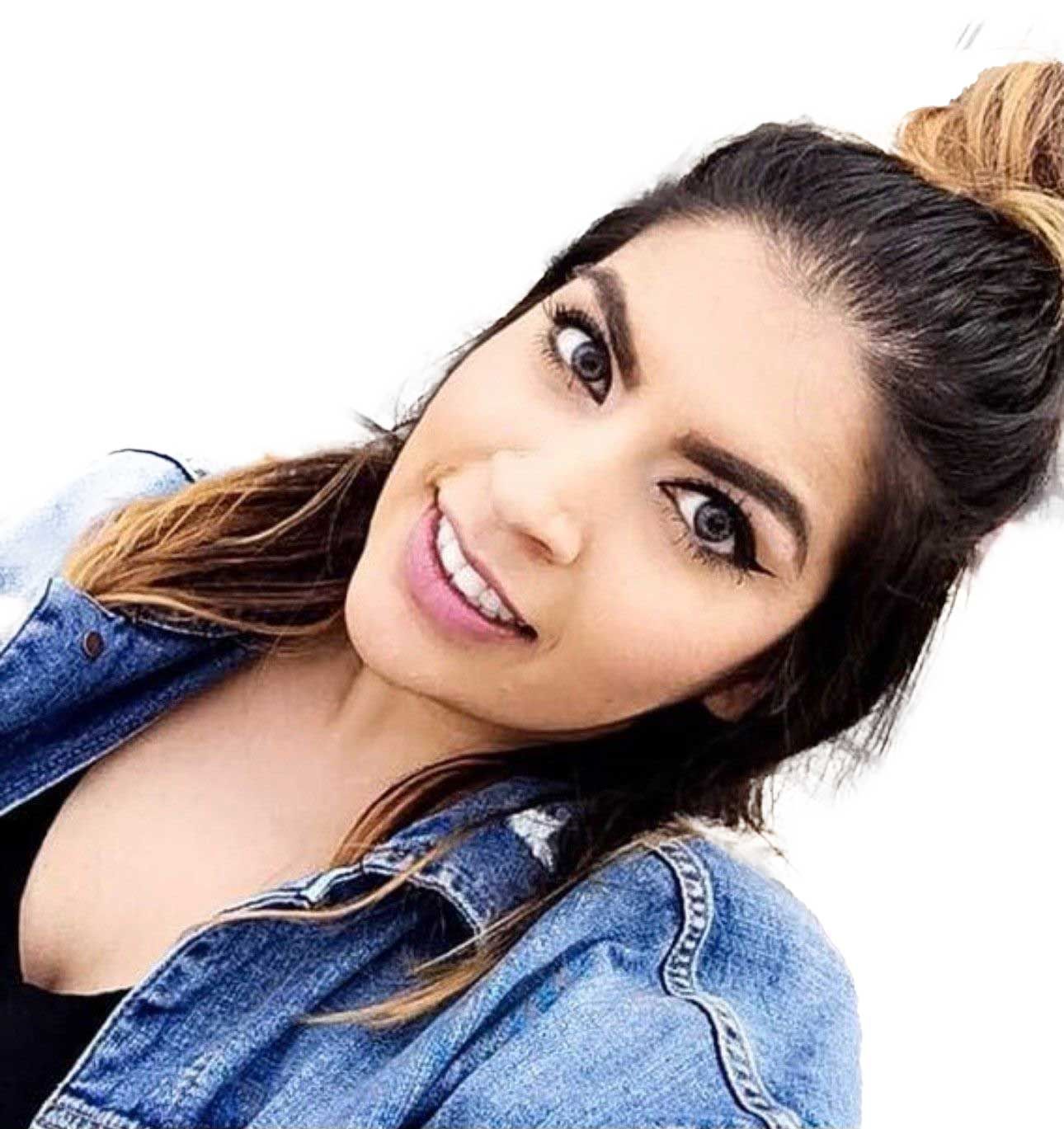 A person with long dark hair styled in a high bun, wearing a denim jacket, looking at the camera with a subtle smile. A person with long dark hair styled in a high bun, wearing a denim jacket, looking at the camera with a subtle smile.
