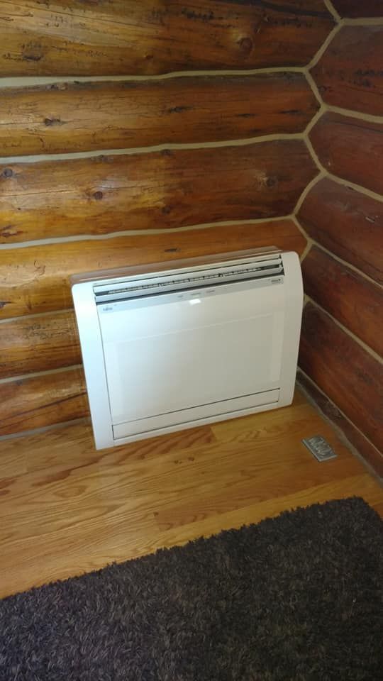 A white heater is sitting in the corner of a log cabin.