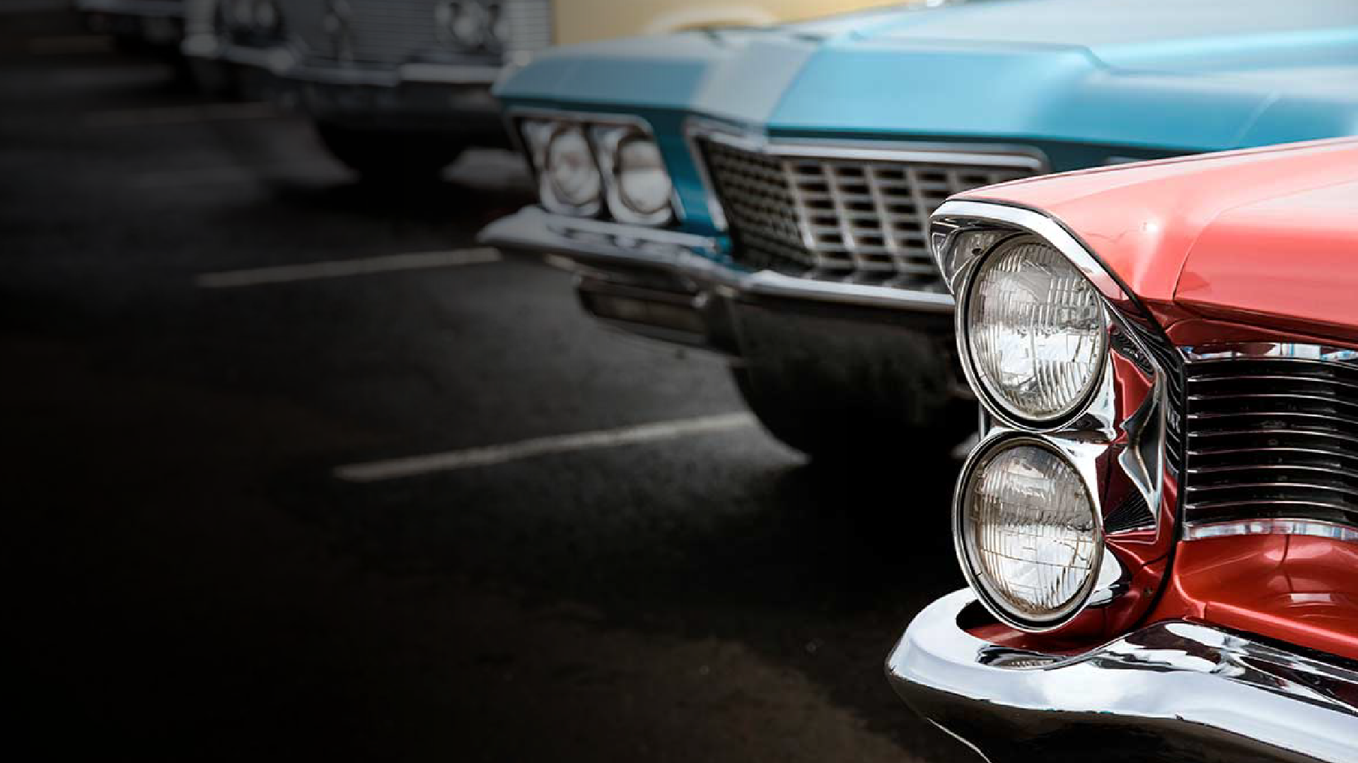A red car is parked next to a blue car in a parking lot.