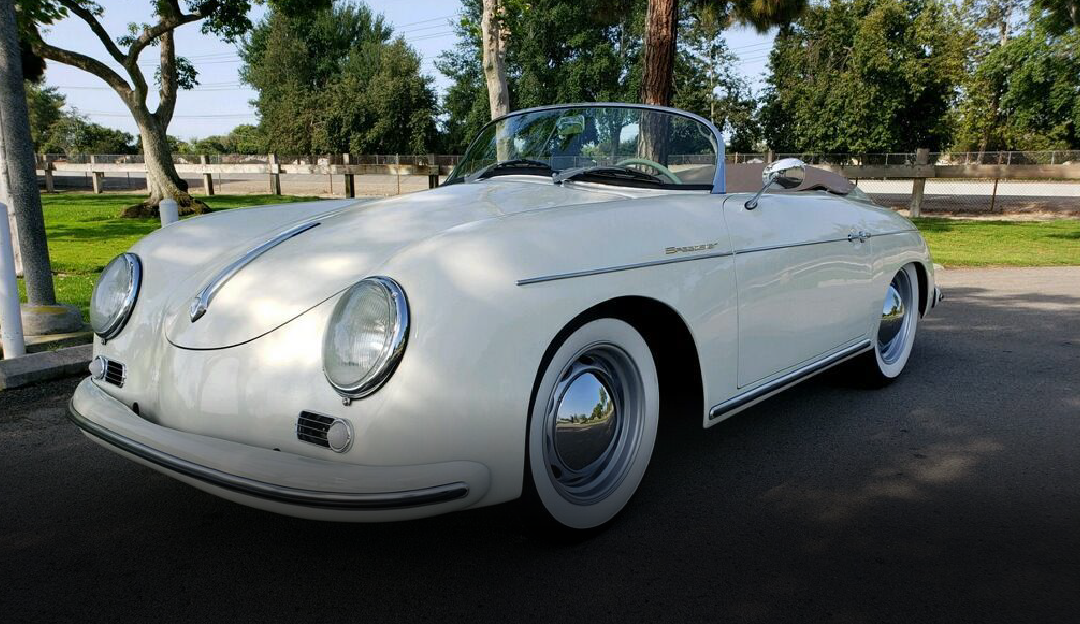 A white porsche speedster is parked on the side of the road.