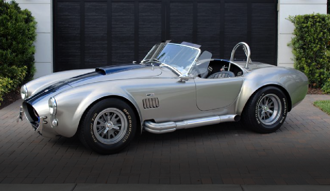 A silver sports car is parked in front of a garage.