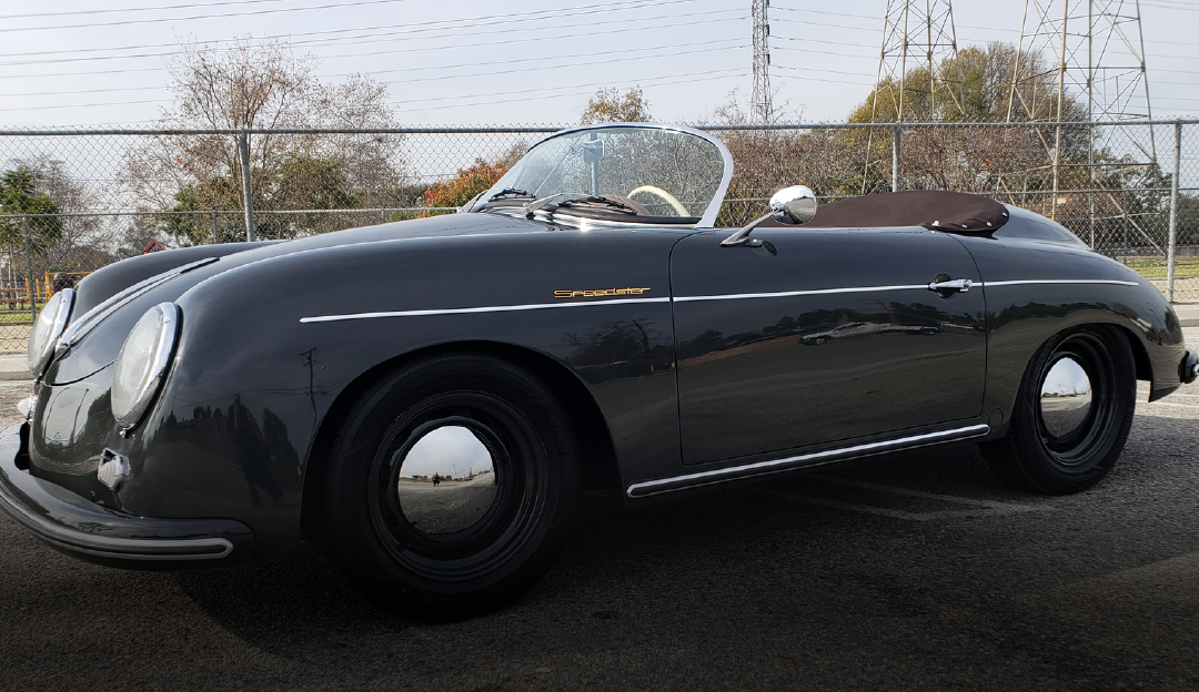 A black porsche speedster is parked on the side of the road.