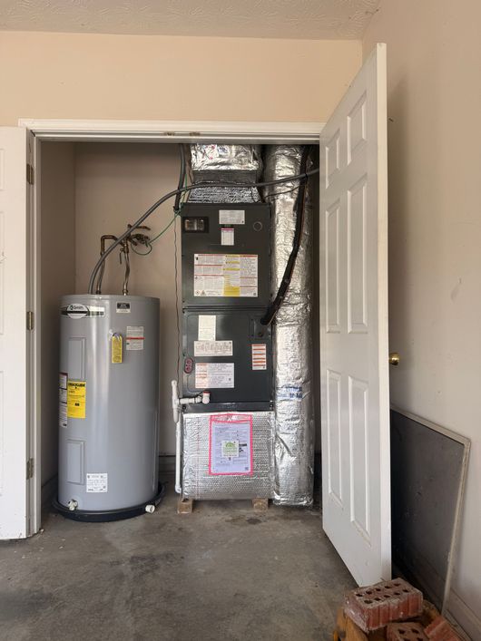 Utility closet with a water heater and HVAC unit, with an open door and foil insulation lining the wall.