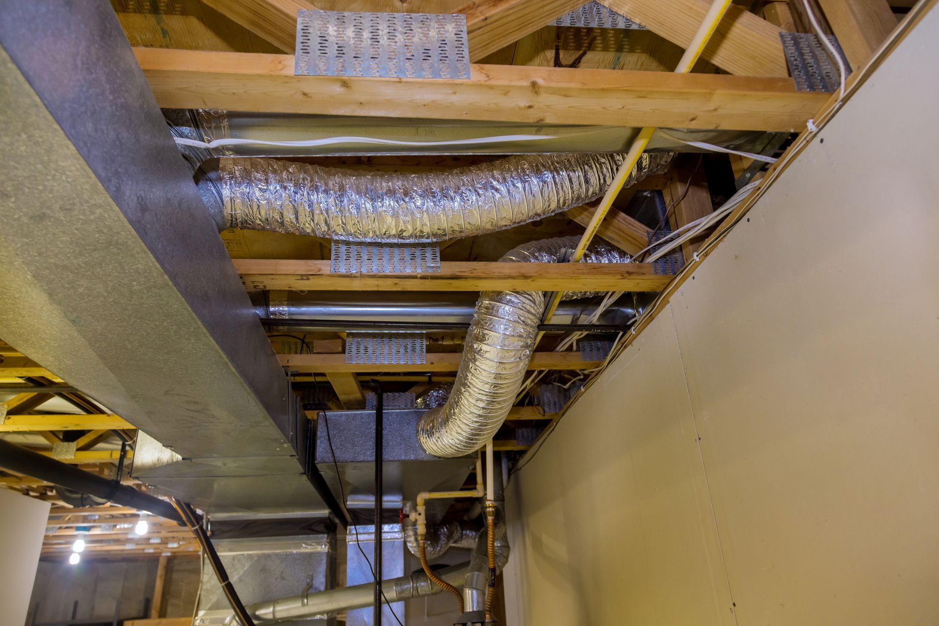 Exposed HVAC ducts and ceiling framing in an unfinished interior space