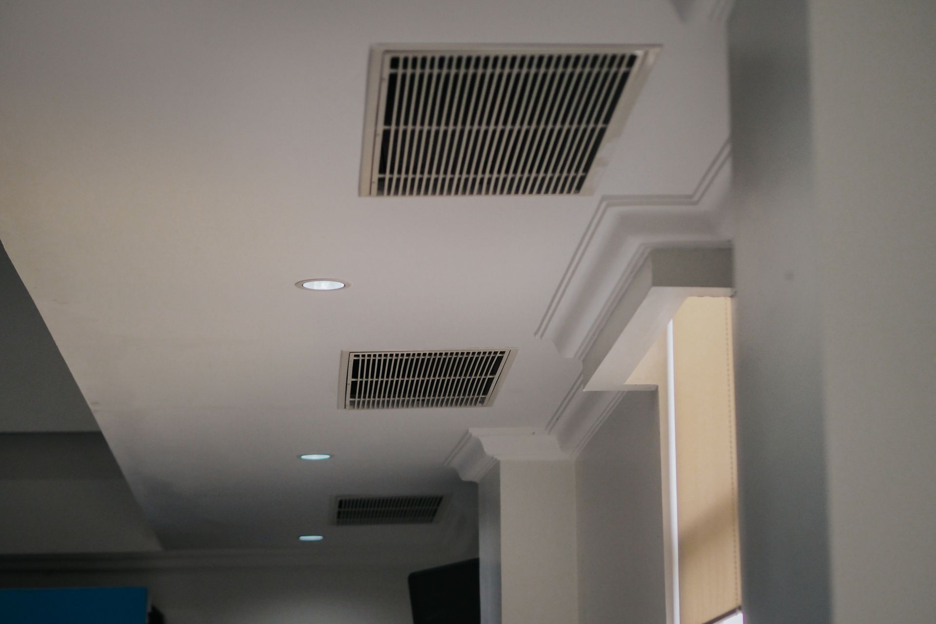 White hallway ceiling with air vents and recessed lights near a doorway