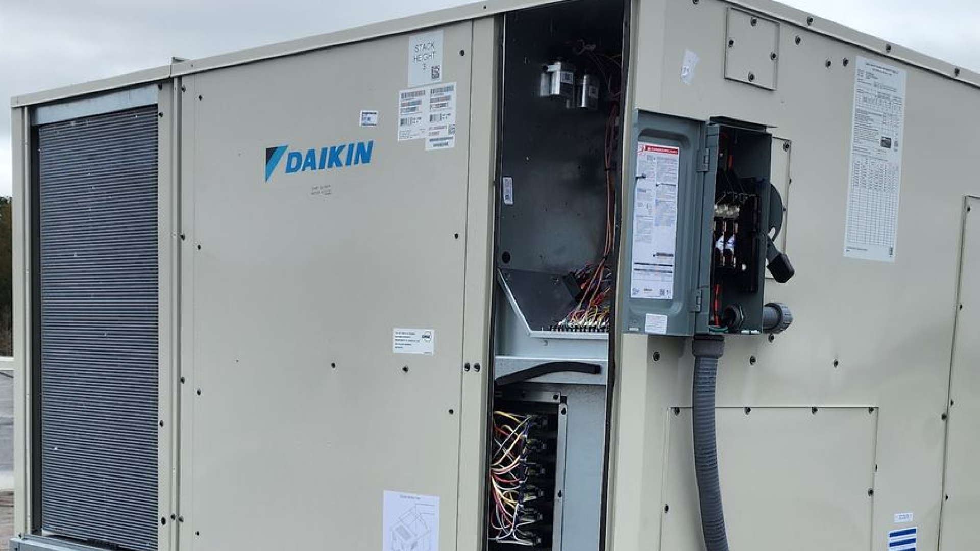 Beige Daikin rooftop HVAC unit with open access panel, electrical components visible.