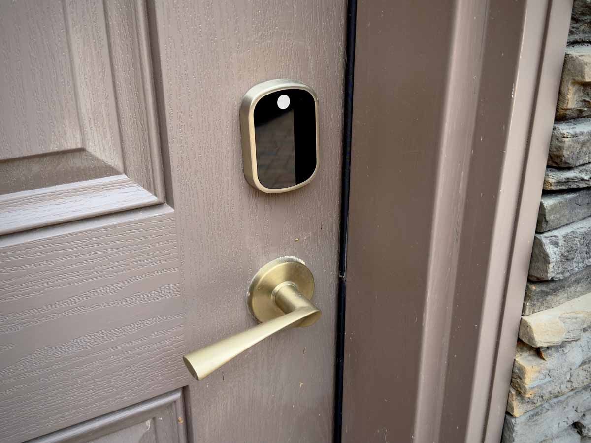 Brown front door with brass handle and a smart doorbell camera near the frame