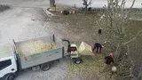 Due operai scaricano detriti da un camion bianco in un cortile accanto a una carriola rossa.