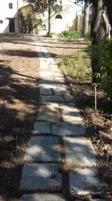 Sentiero di pietra che attraversa un cortile ombreggiato e conduce a una casa
