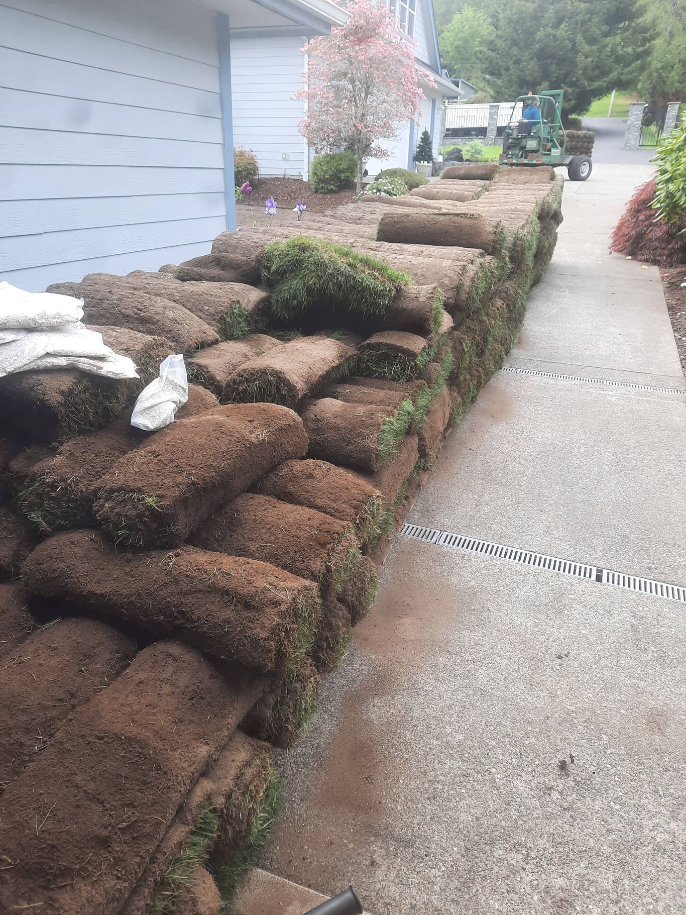 Stone retaining wall with stacked brown rocks beside a sidewalk and apartment building exterior.