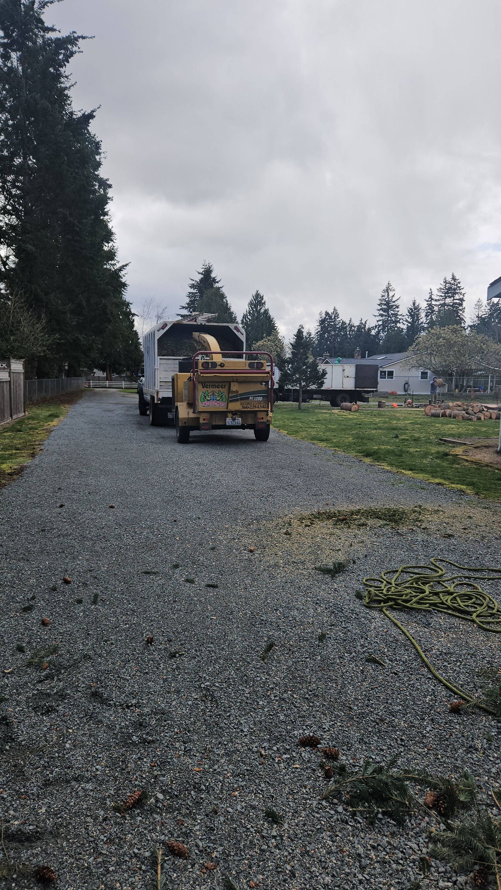 Gravel driveway with a construction truck parked near houses under a gray sky