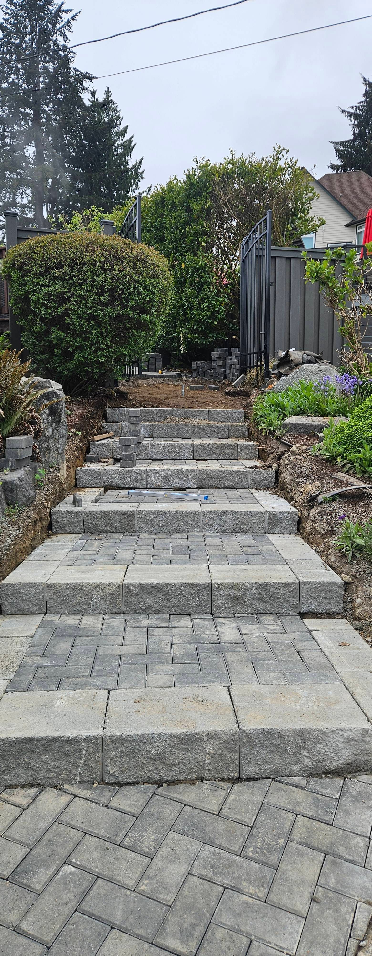 Stone steps leading up a landscaped garden path with shrubs and a wooden gate