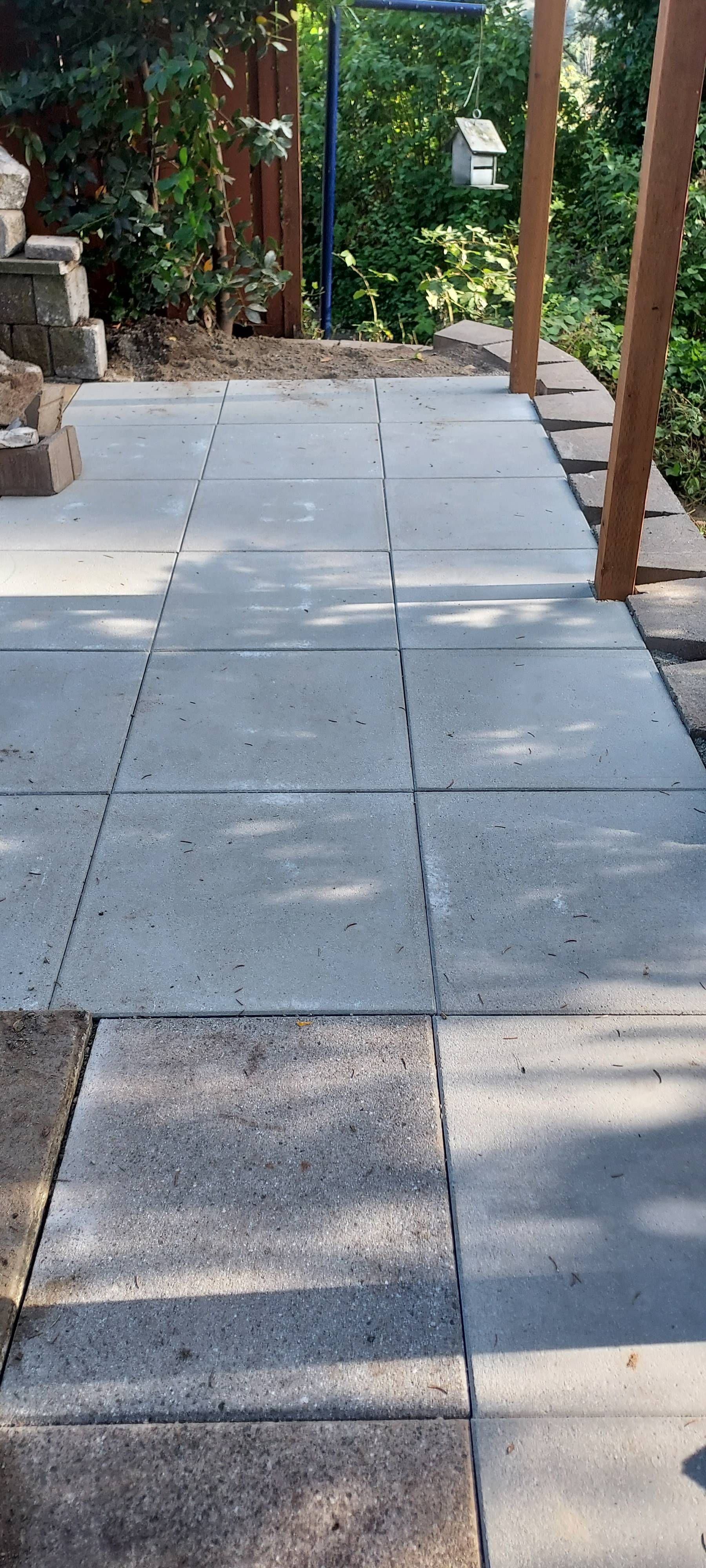 Garden walkway with large gray paving stones beside greenery and a wooden bench