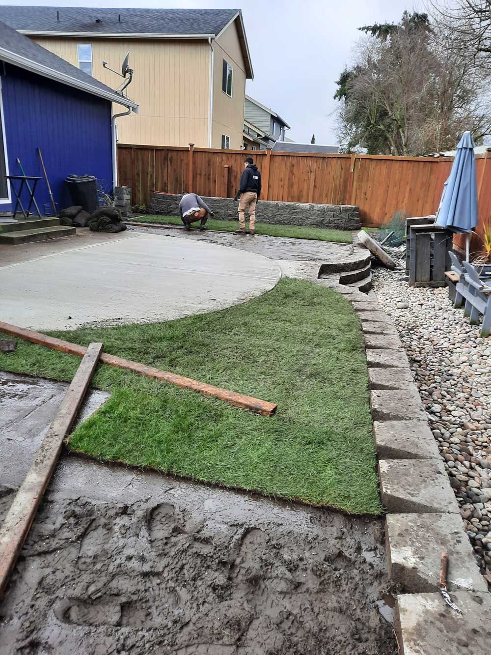 A man is working on a lawn in a backyard.