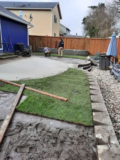 A man is working on a lawn in a backyard.