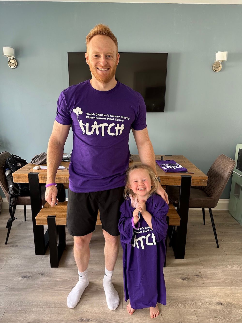 Website Sorted Three Peaks Challenge | A man and a little girl are standing next to each other in a living room.