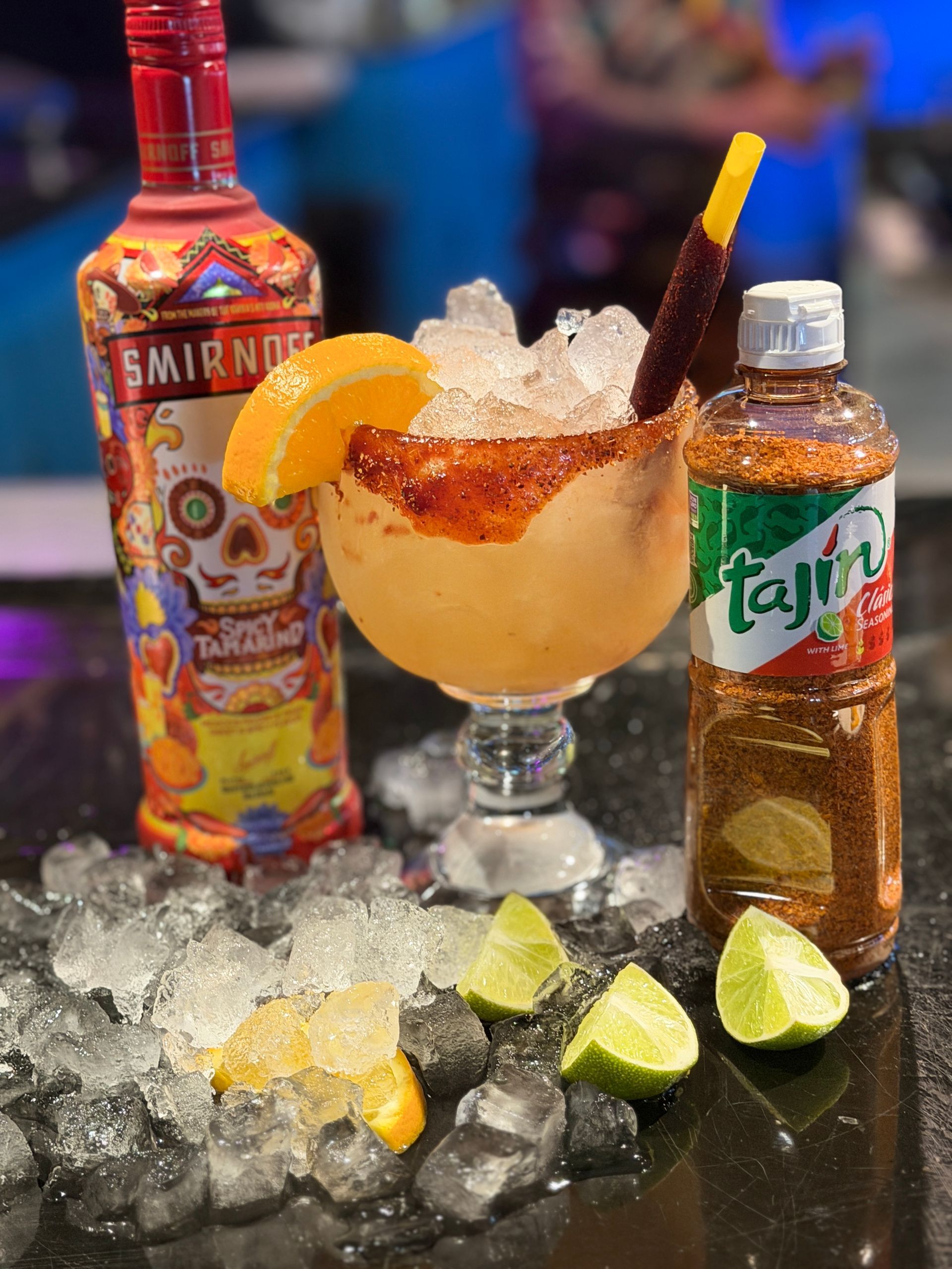 Colorful cocktail with ice, lime wedges, and liquor bottles on a bar counter