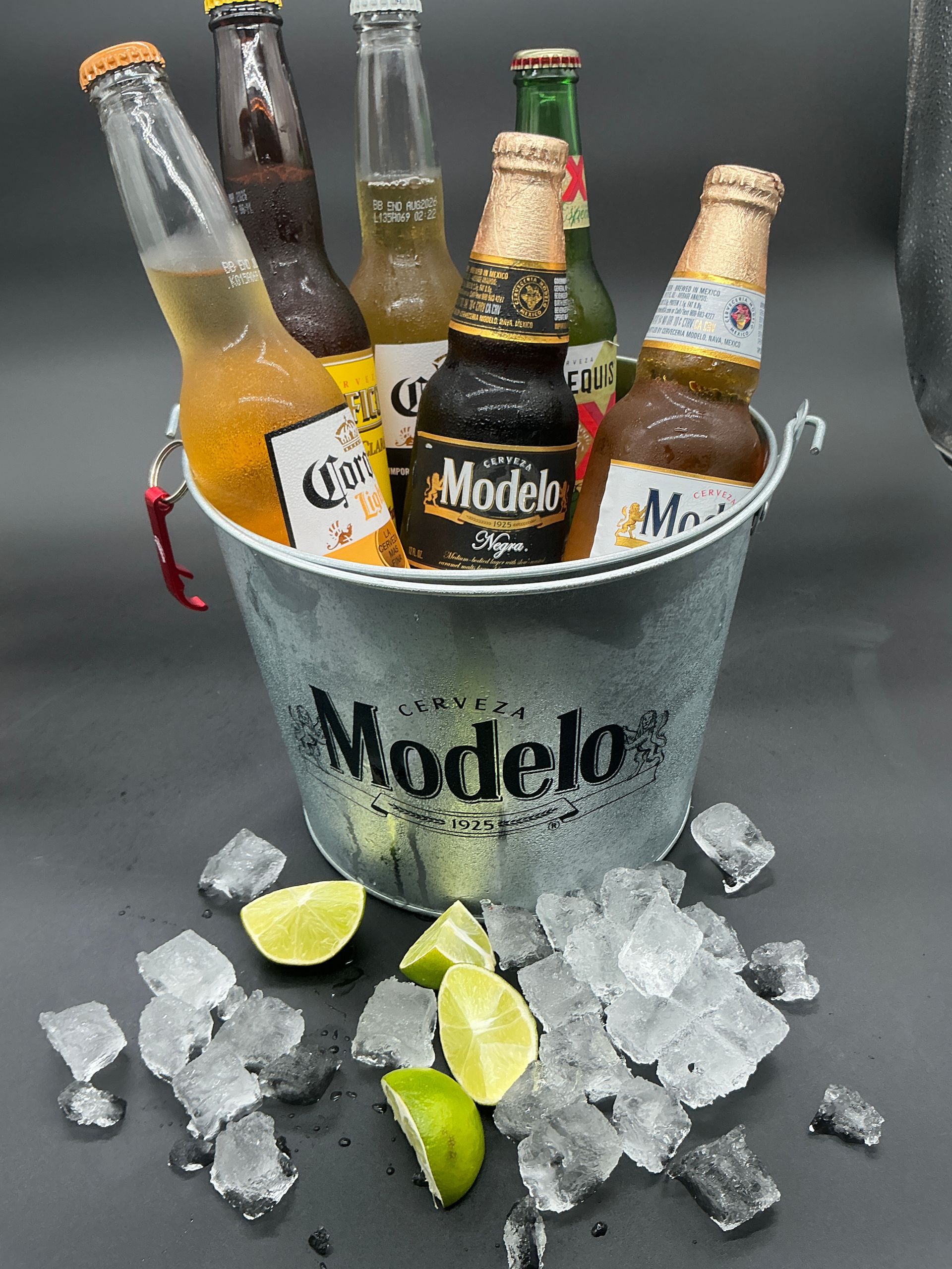 Modelo beer bottles in an ice bucket with lime wedges scattered around them