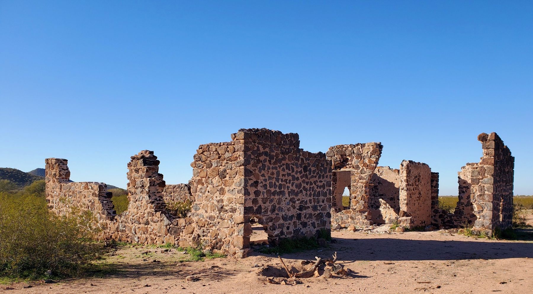 Stone ruins under a clear blue sky in a desert landscape.