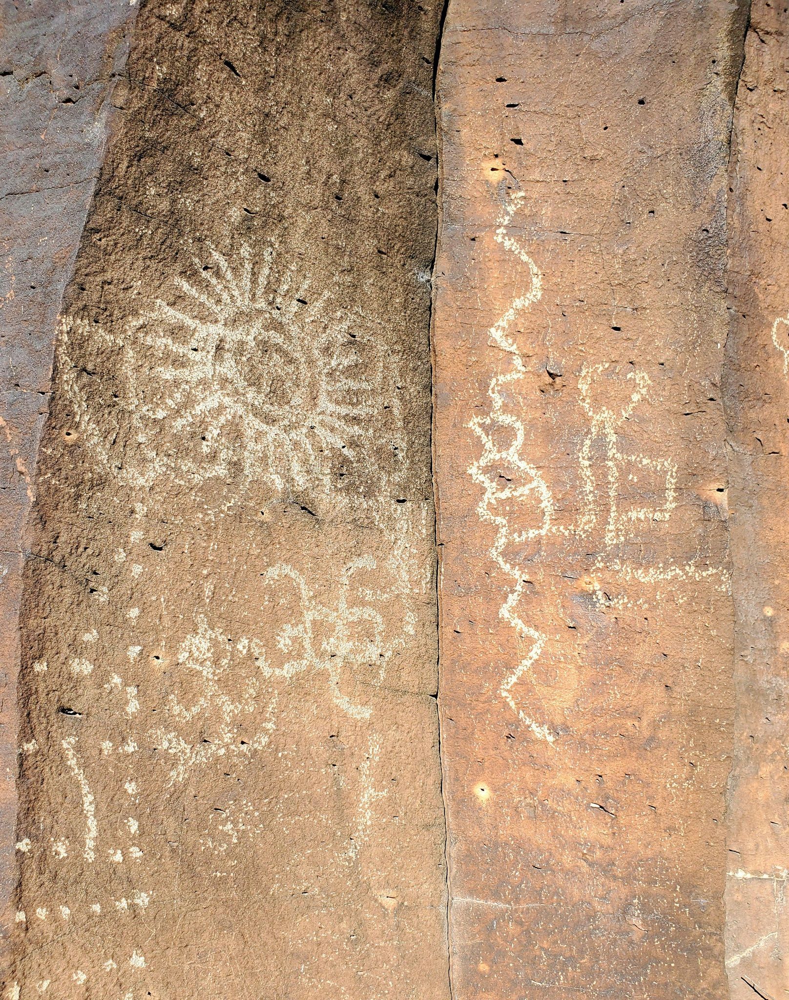 Petroglyphs carved into rock. Left panel: sun-like pattern and zigzag lines. Right panel: humanoid figure.