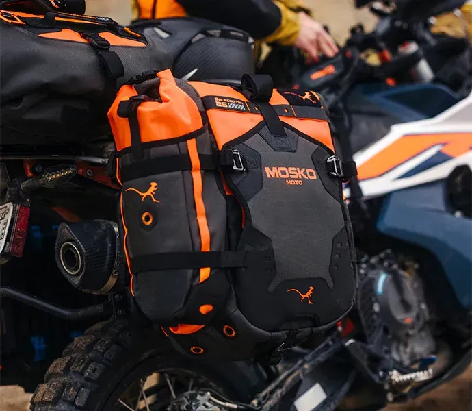 Orange and black Mosko Moto motorcycle panniers mounted on a bike.