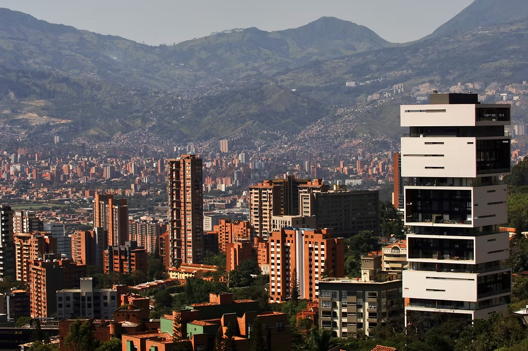 Cityscape with mountains in the background, featuring modern white and brown high-rise buildings.
