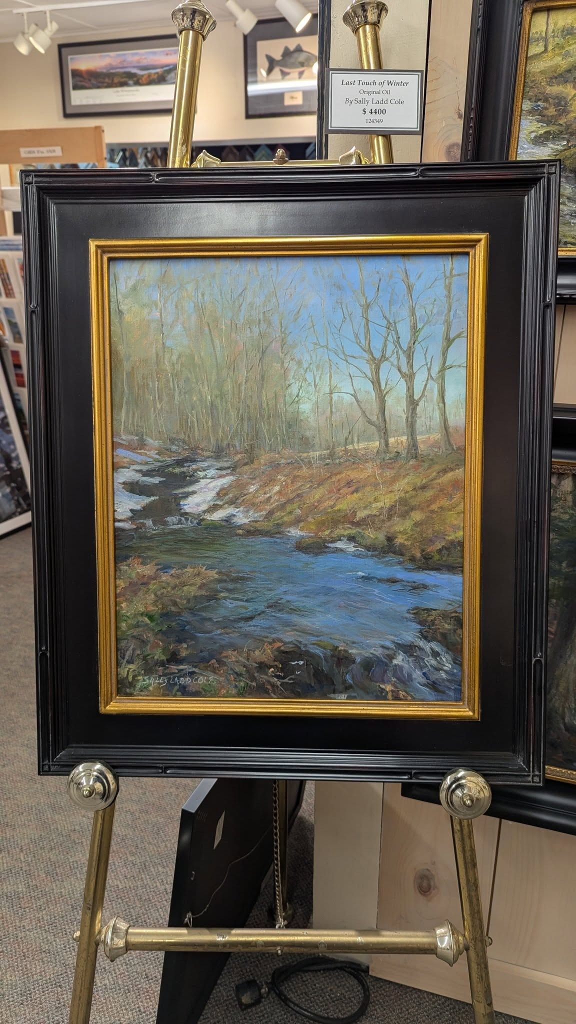 Snowy winter scene with tall trees, a bright sun, and a frozen lake, framed in gold.
