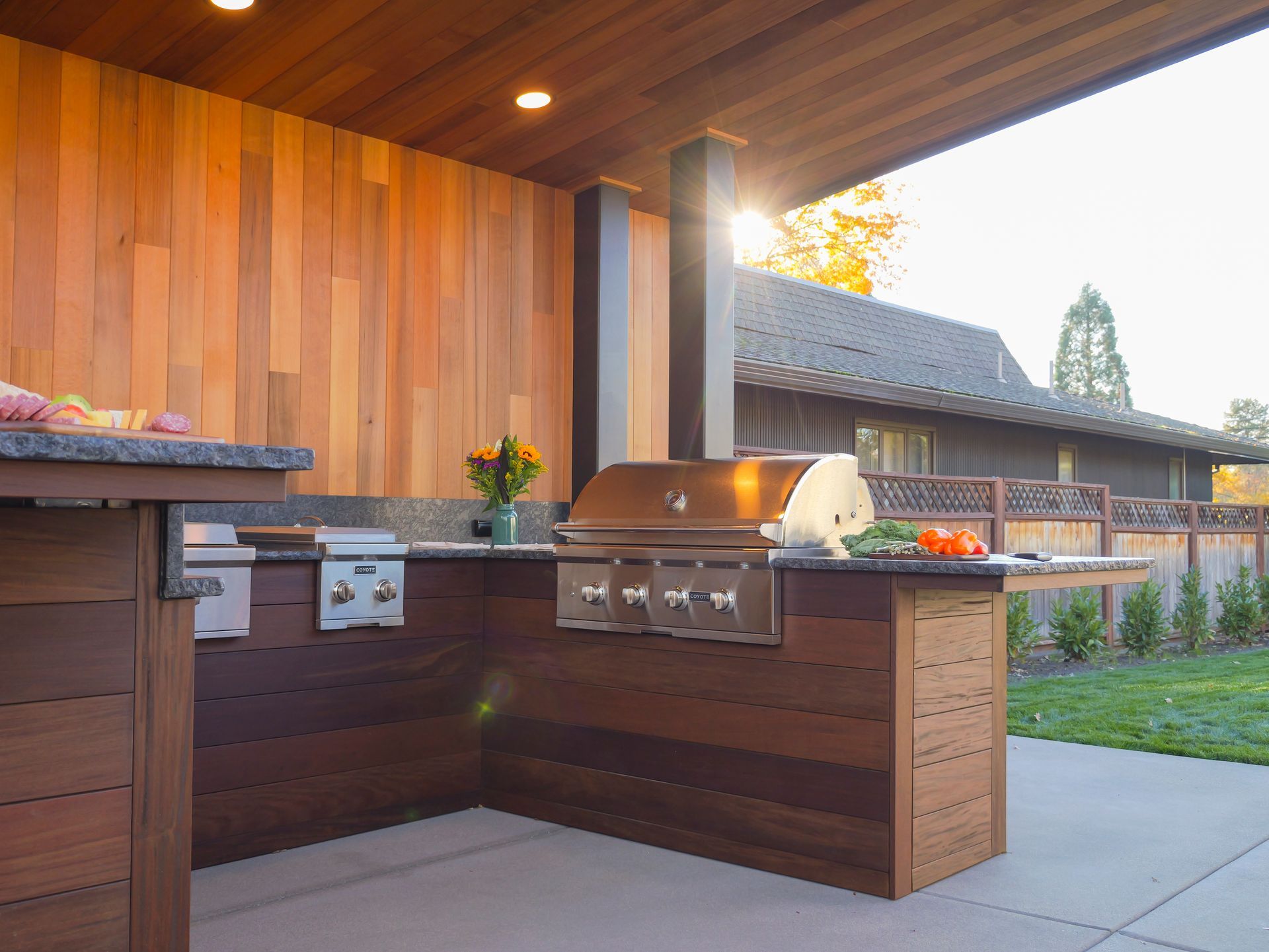 An outdoor kitchen with a grill and wooden cabinets