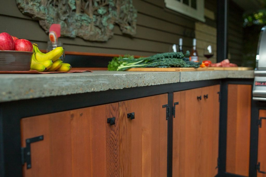 Outdoor kitchen with wood cabinets, concrete countertop, and food.