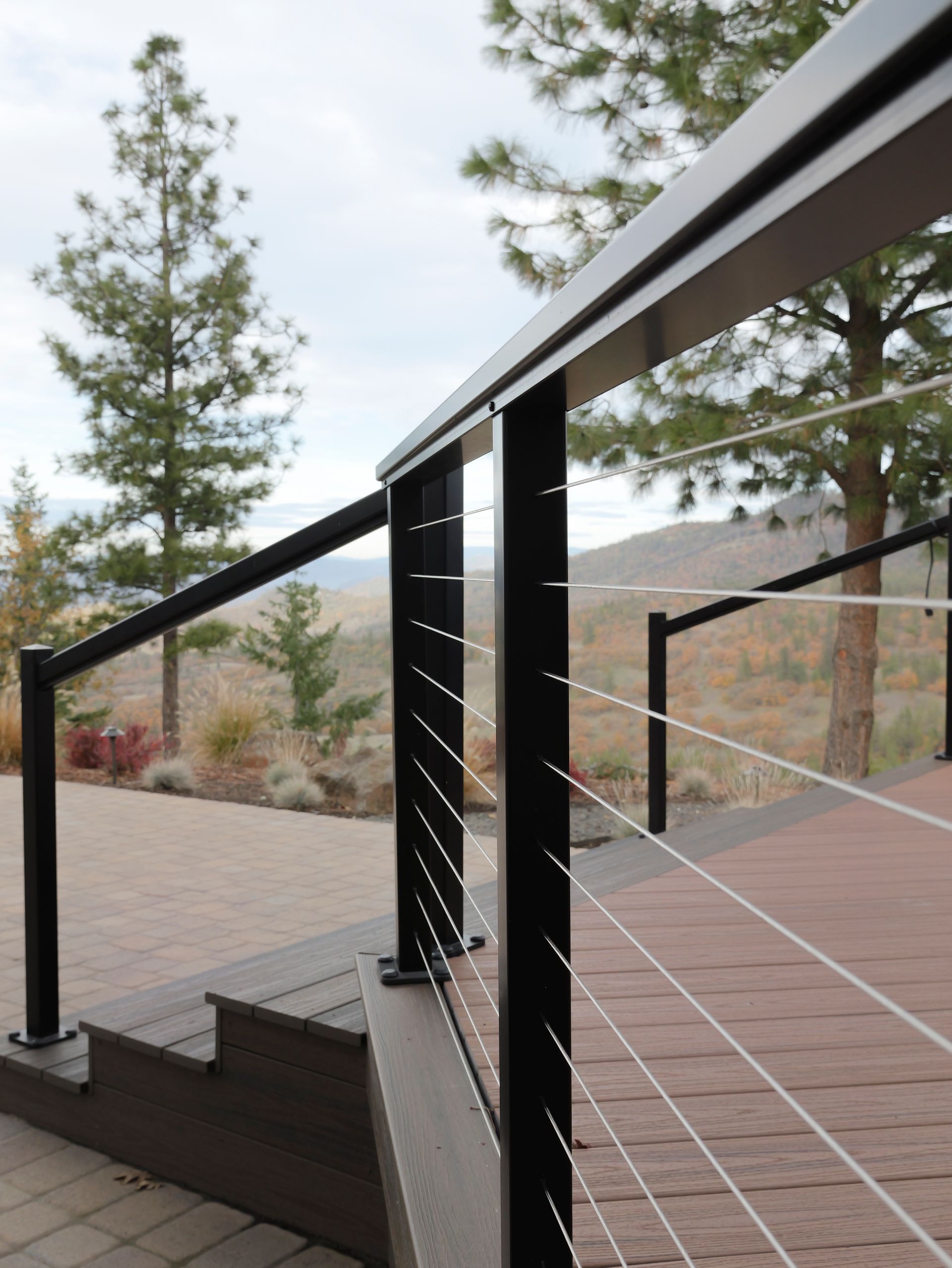 Black deck railing with cable wires and wood deck, set outdoors.
