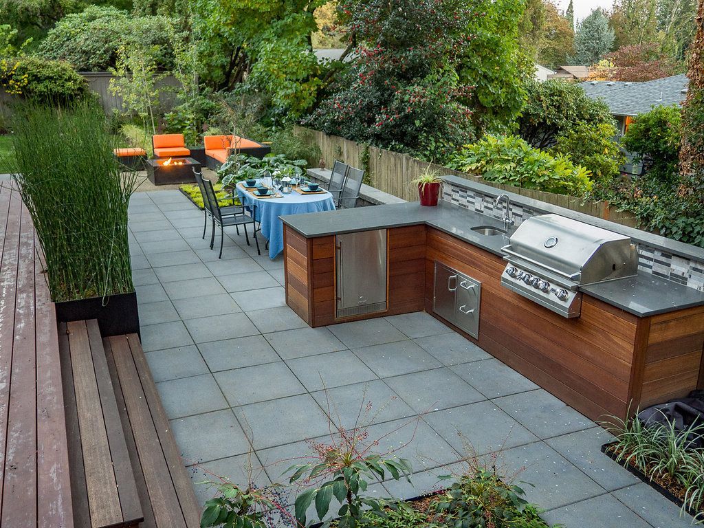 A patio with a table and chairs and a grill.