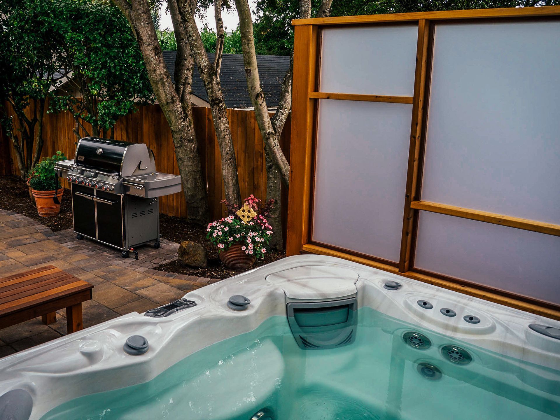 A hot tub is sitting in a backyard next to a grill.