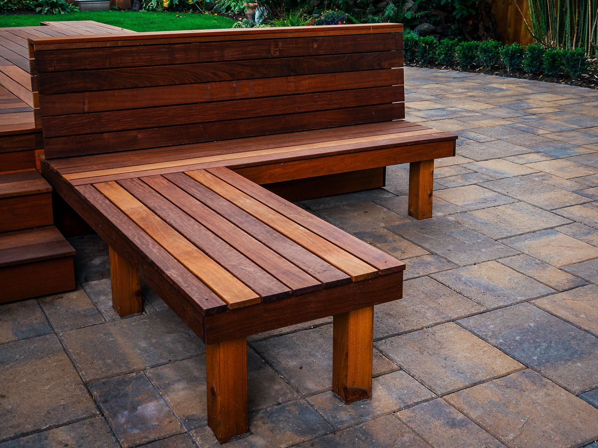 A wooden bench is sitting on a brick patio.