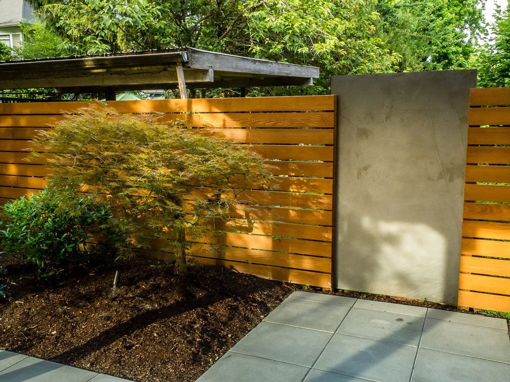 A wooden fence with a concrete wall behind it
