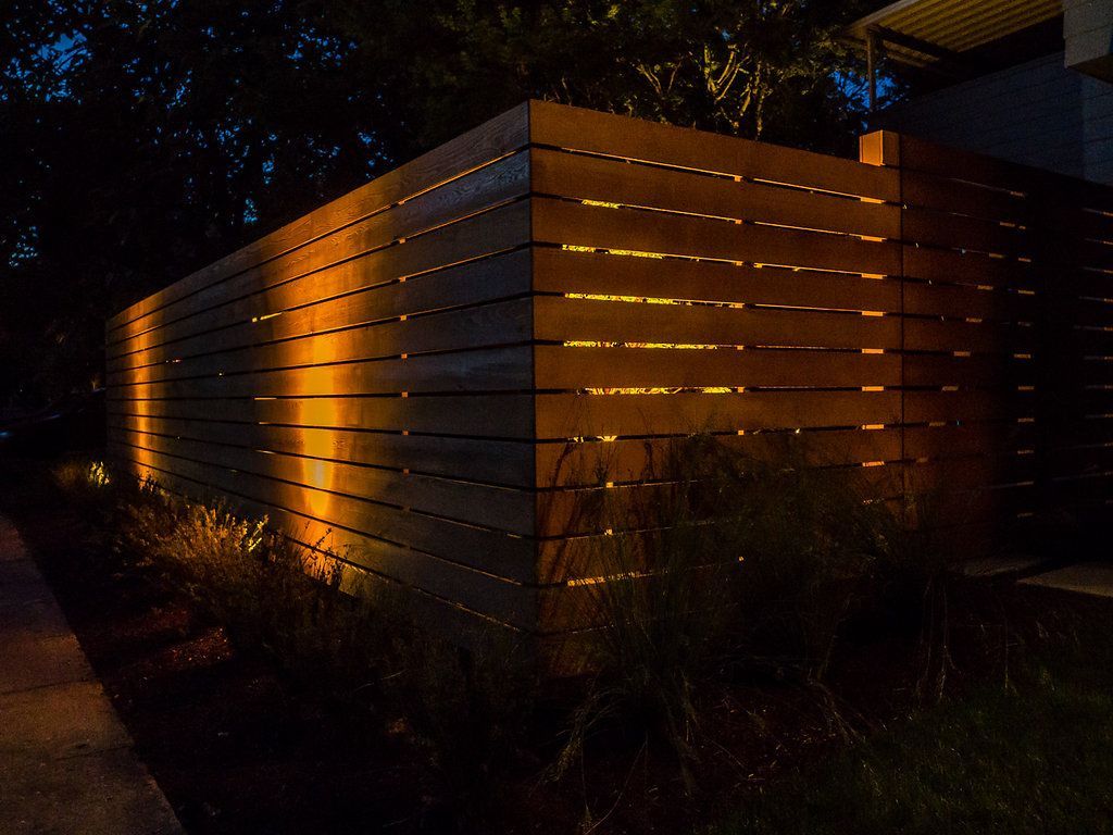 A wooden fence is lit up at night