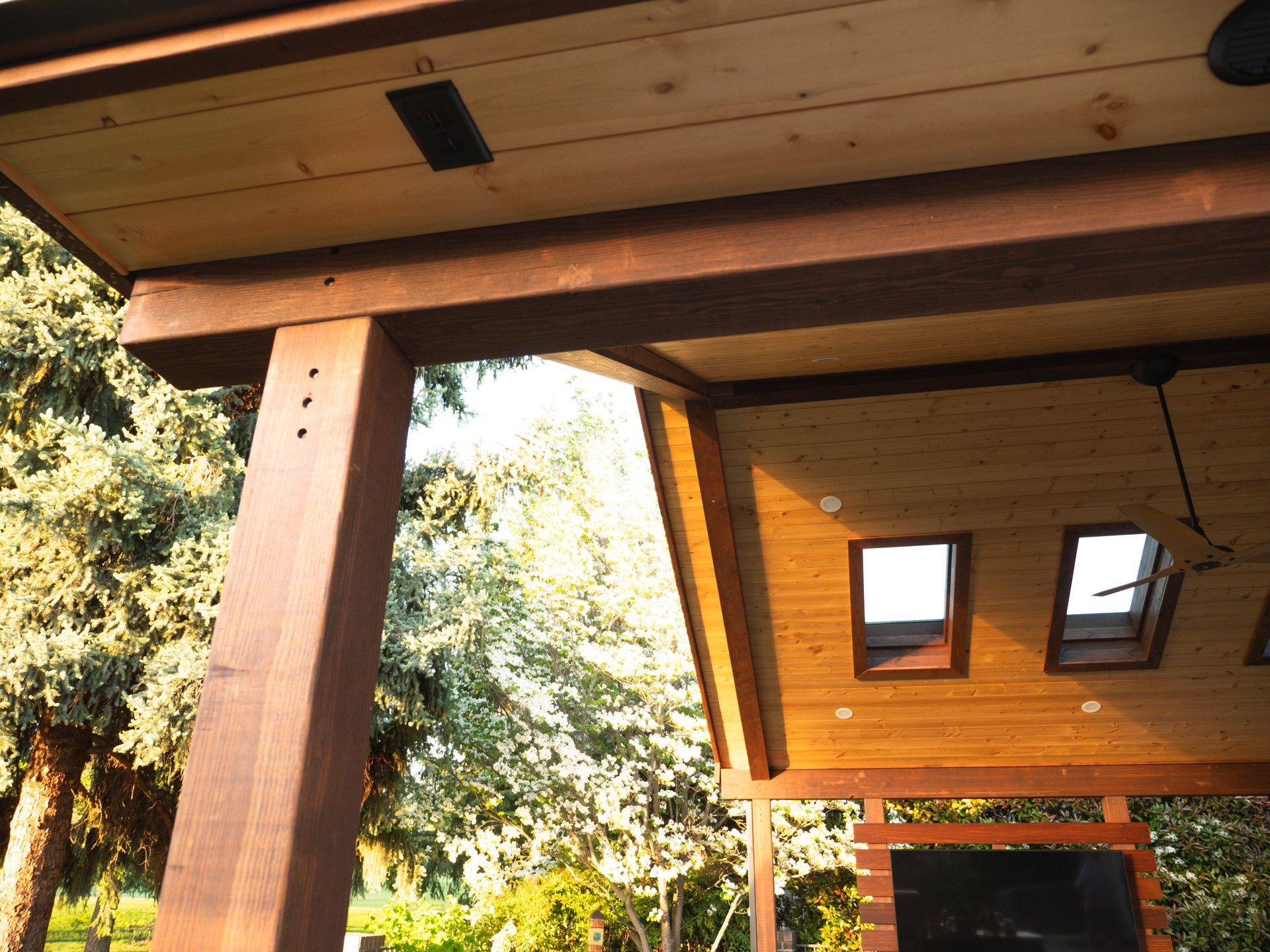Wooden outdoor structure with beams, skylights, and natural light.