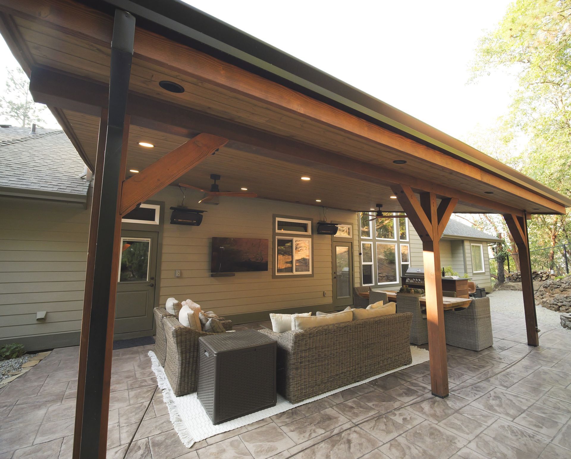 Patio with bar, seating, and built-in grill under a wooden awning.
