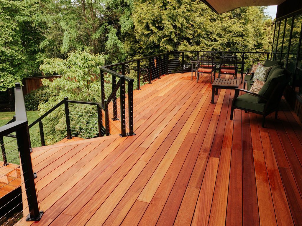 Wooden deck with black railings, outdoor furniture, and surrounding trees.