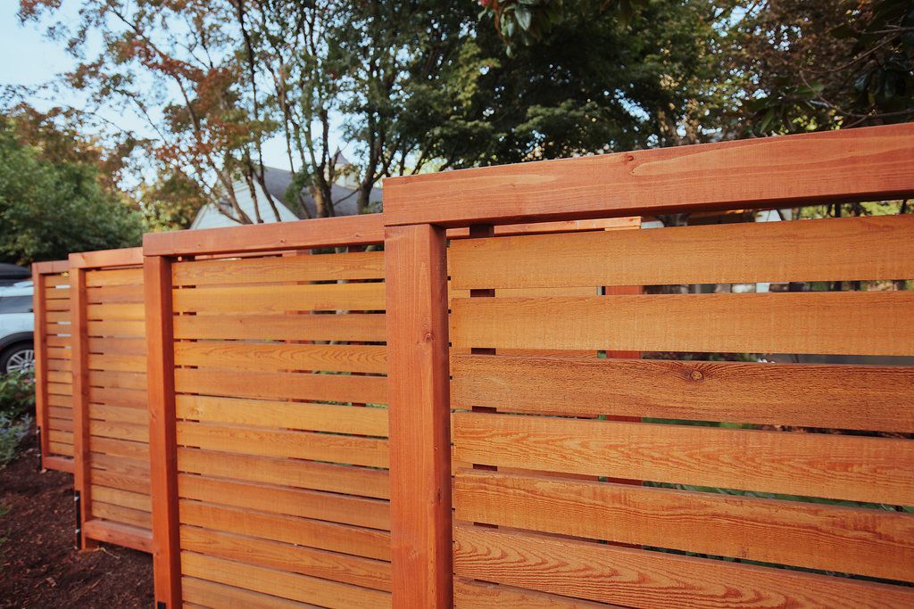 A wooden fence with a car parked in the background.