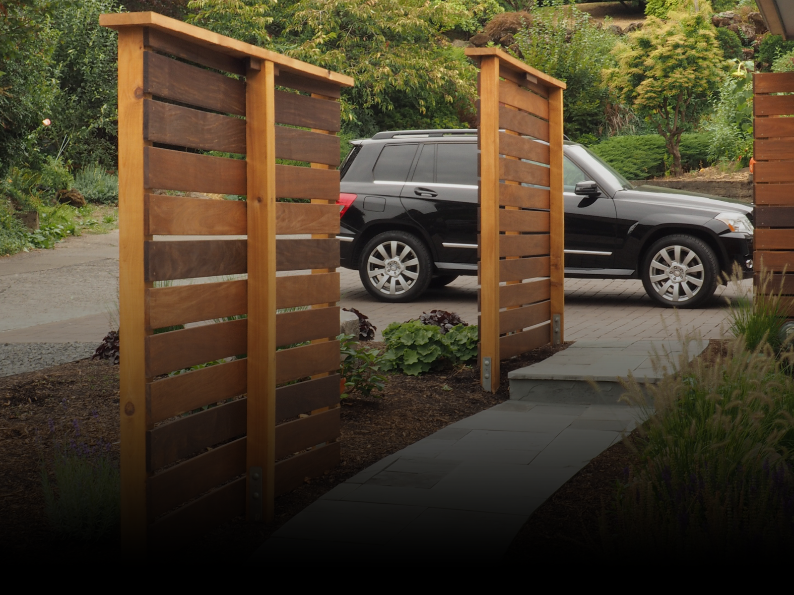 A black suv is parked behind a wooden fence