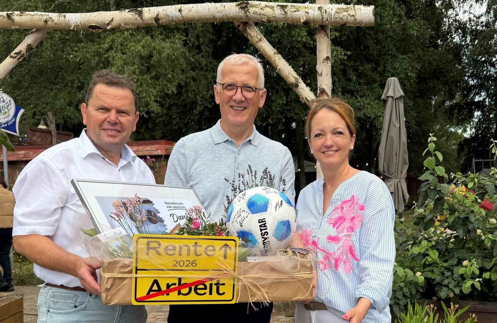 Drei Personen, die einen Korb mit Geschenken und ein gelbes Schild mit der Aufschrift „Arbeit“ halte