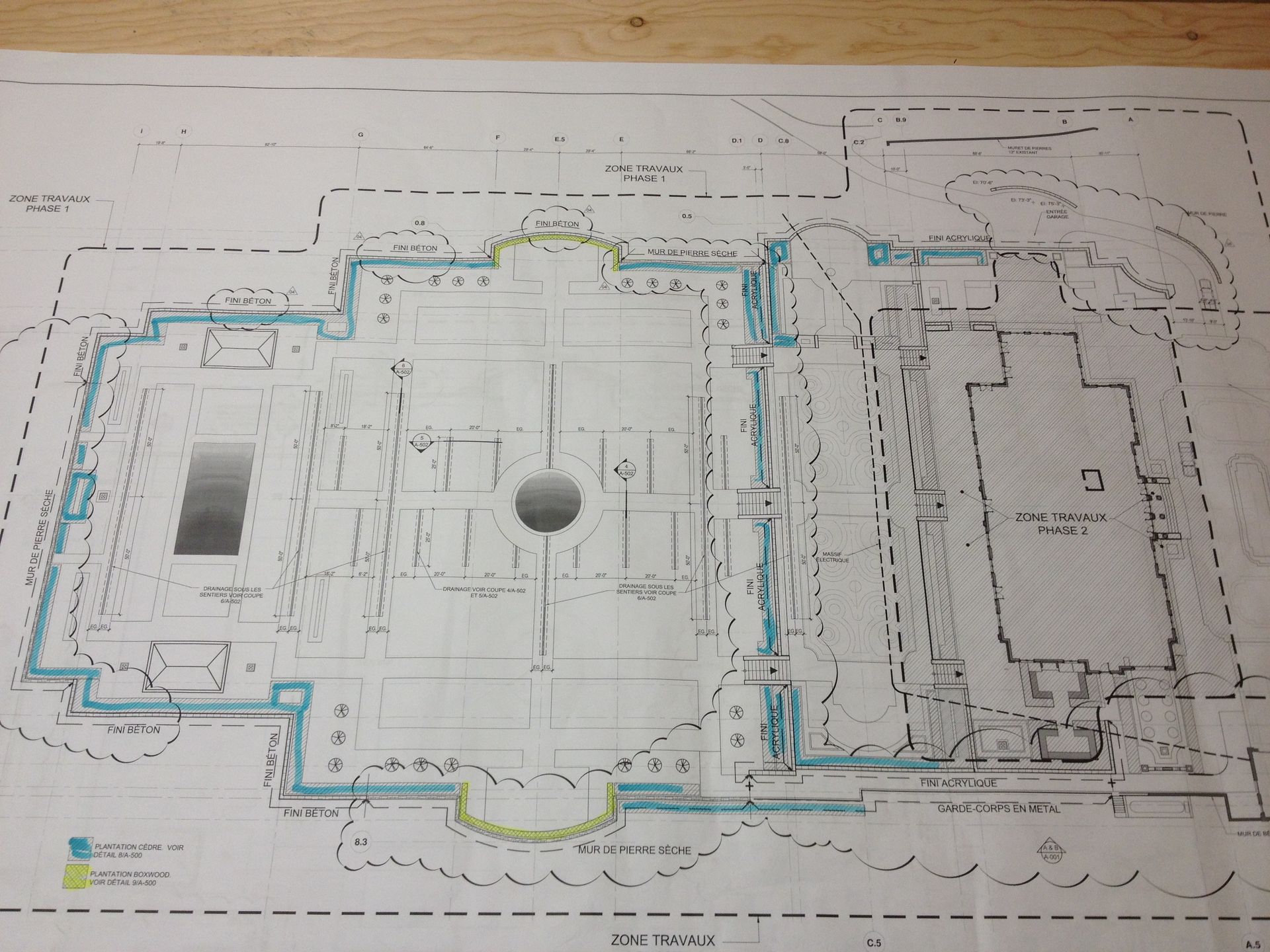 Plan architectural d'un bâtiment avec un grand élément circulaire. Les lignes bleues et jaunes indiquent les détails.