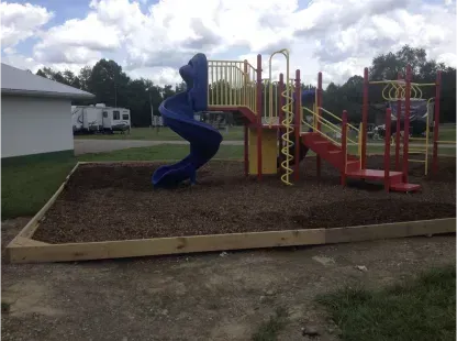 Blue spiral slide and red playground structure on a mulch-covered play area outdoors.