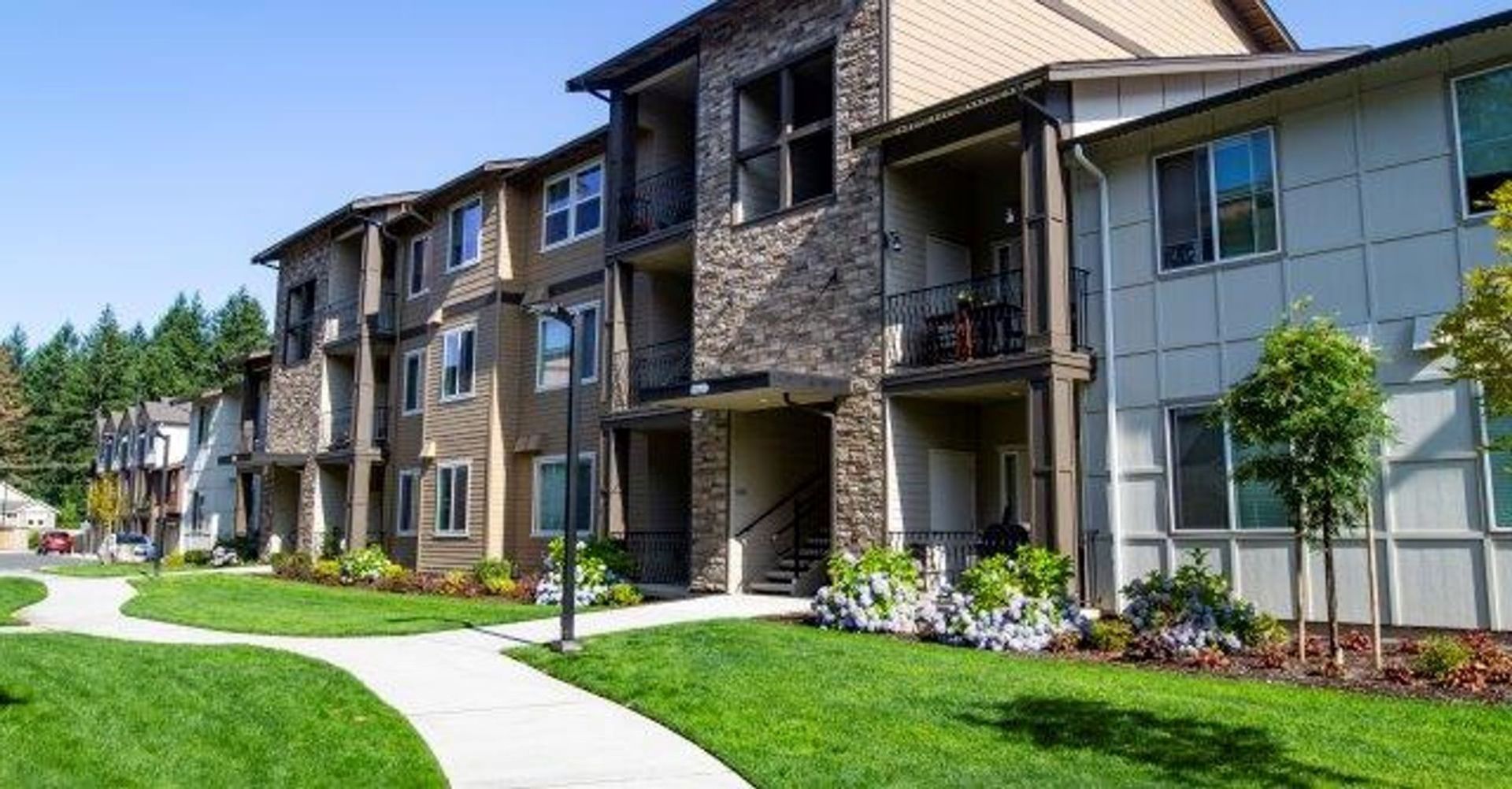 A large apartment building with a lush green lawn in front of it.