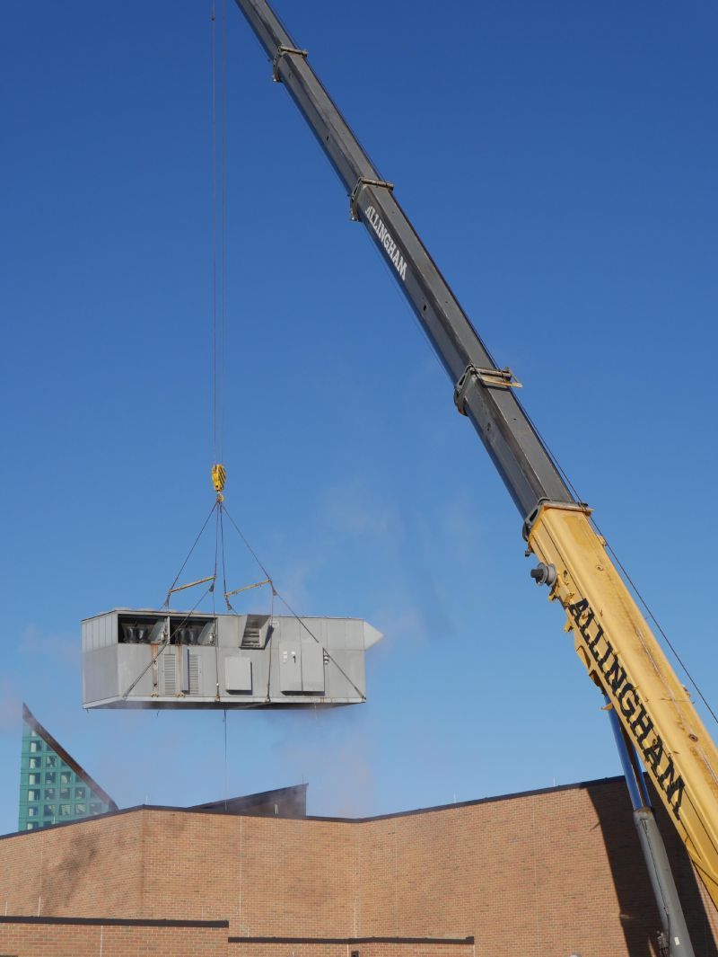 Crane Lifting HVAC Unit Above Building.