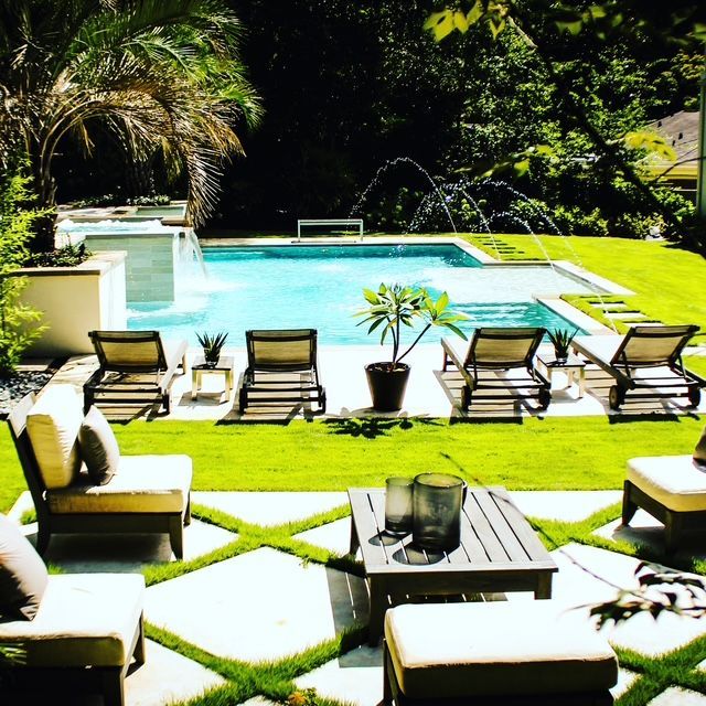 Luxurious backyard with a swimming pool, lounge chairs, and a patio with seating.