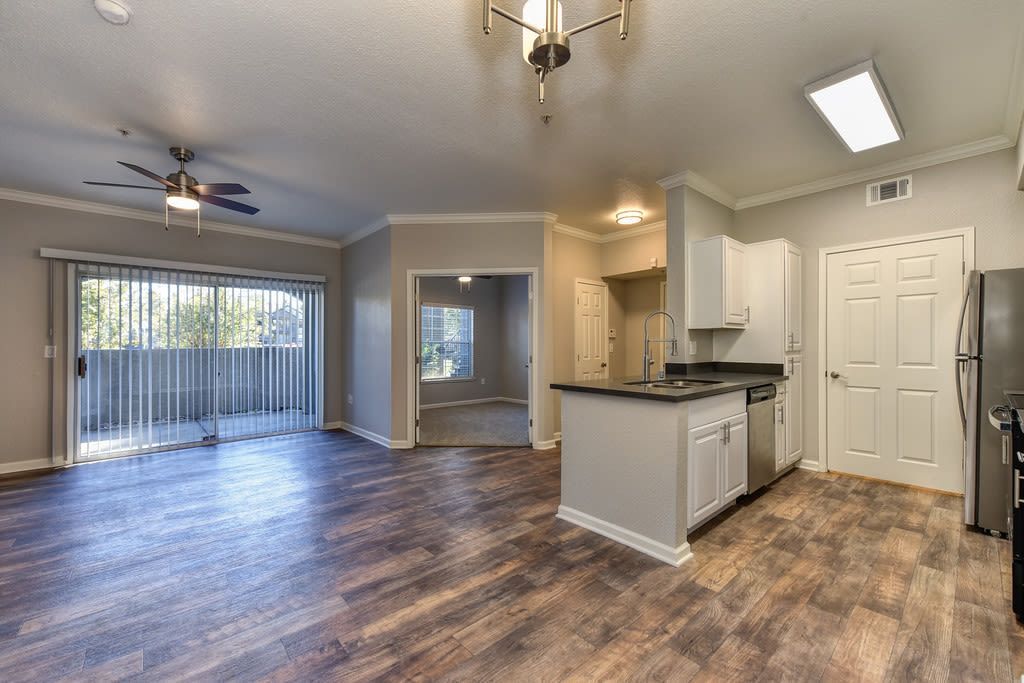 Open-concept apartment with wood floors. Kitchen on the right, living area and balcony on the left at River Oaks.